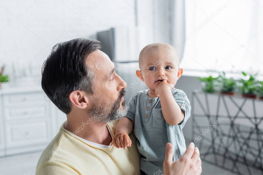 Mature parent looking at toddler child at home 