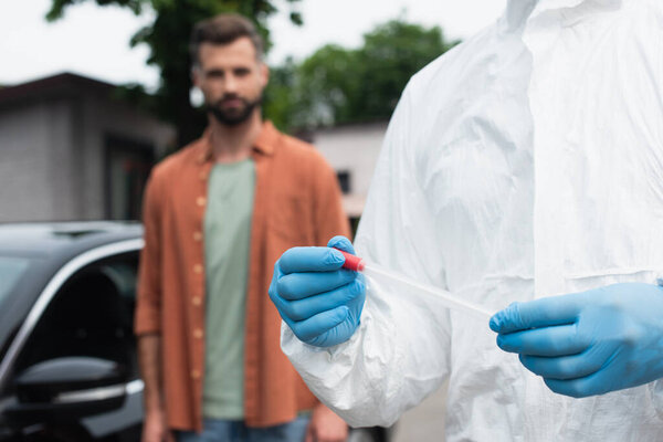 Medical worker in latex gloves holding pcr test near blurred driver 