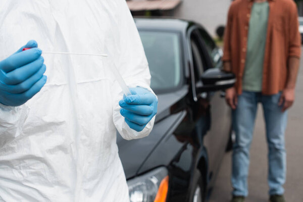 Cropped view of medical worker holding pcr test near blurred driver and car outdoors 