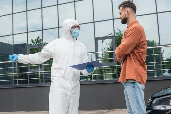 Mediziner Schutzanzug Hält Klemmbrett Und Zeigt Mit Der Hand Die — Stockfoto