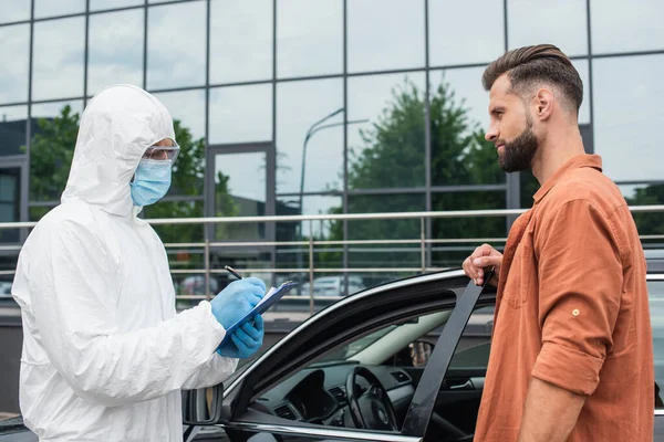 Driver Standing Car Medical Worker Hazmat Suit Writing Clipboard — Stock Photo, Image