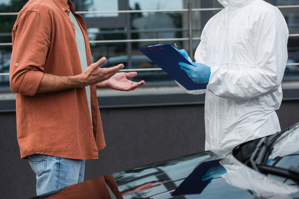 Cropped view of driver standing near border guard writing on clipboard and auto 