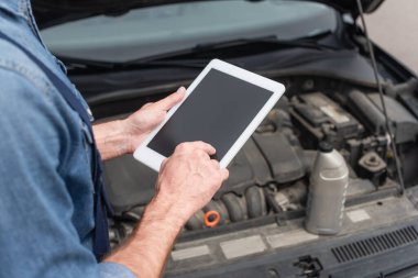 Bulanık arabanın yanında dijital tablet kullanan tamircinin kırpılmış görünümü 