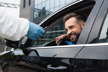 PCR testi olan bir sağlık çalışanının yanında gülümseyen bir sürücü. 