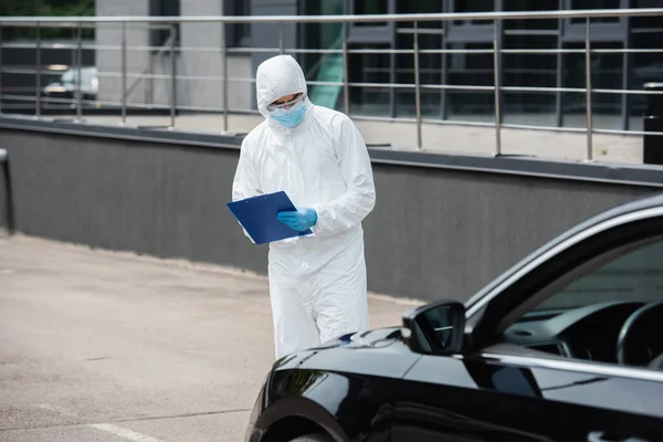 Medical Worker Hazmat Suit Goggles Writing Clipboard Blurred Car — Stock Photo, Image