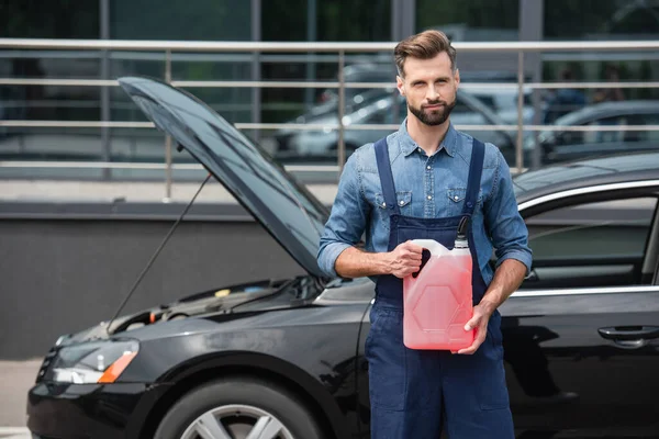 Mechanic Holding Canister Windshield Washer Fluid Looking Camera Blurred Car — Stock Photo, Image