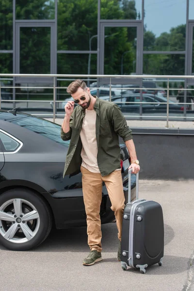 Turista Gafas Sol Sosteniendo Maleta Cerca Coche Aire Libre —  Fotos de Stock