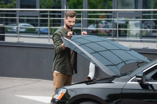 Young driver opening hood of car outdoors