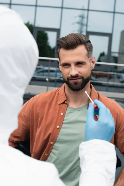 Trabalhador Médico Desfocado Terno Hazmat Segurando Teste Pcr Perto Homem — Fotografia de Stock