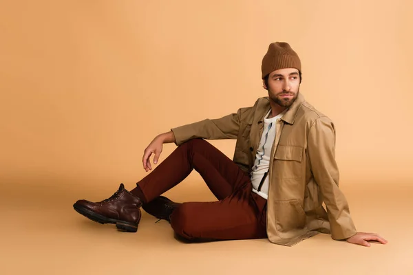 Trendy Man Stylish Autumn Outfit Looking Away While Sitting Beige — Zdjęcie stockowe