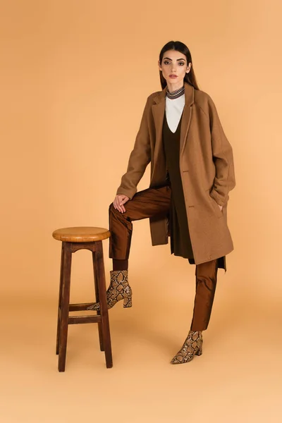 Trendy Woman Holding Hand Pocket Coat While Posing High Stool — Foto de Stock