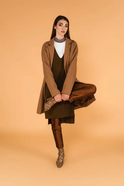 Fashionable Woman Brown Coat Leather Boots Posing One Leg Beige — Zdjęcie stockowe