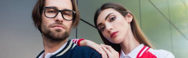 man in eyeglasses looking at camera near stylish woman leaning on his shoulder, banner clipart