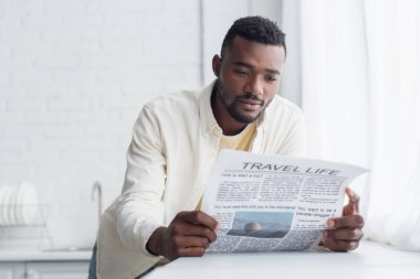 Afro-Amerikan gömlekli adam seyahat gazetesi okuyor. 