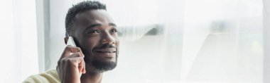 Gülümseyen Afrikalı Amerikalı adam cep telefonuyla konuşuyor.