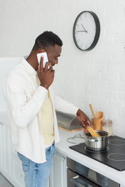 Joven Afroamericano Hombre Hablando Por Celular Cocinar Espaguetis Cocina —  Fotos de Stock