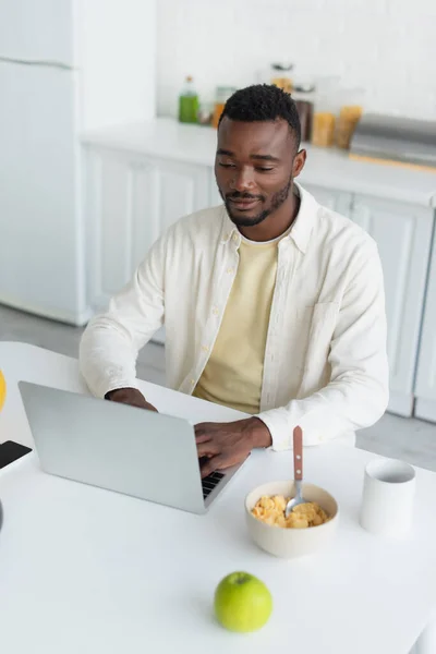 Felice Giovane Uomo Africano Americano Utilizzando Computer Portatile Vicino Cornflakes — Foto Stock