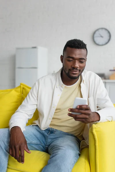 Allegro Uomo Africano Americano Utilizzando Smartphone Mentre Seduto Sul Divano — Foto Stock