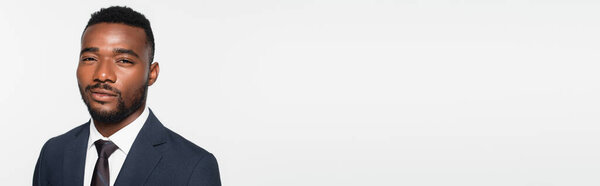 улыбающийся африканский американский бизнесмен в костюме, изолированном на сером баннере