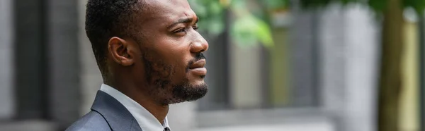 side view of bearded african american businessman in suit looking away, banner