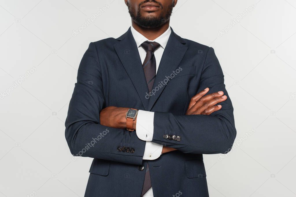 cropped view of african american man in suit standing with crossed arms isolated on grey