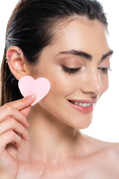 пронзительная и улыбающаяся женщина, держащая губку в форме сердца изолированную на белом 