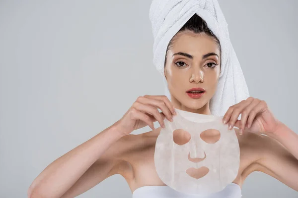 Jonge Vrouw Met Handdoek Hoofd Holding Sheet Masker Geïsoleerd Grijs — Stockfoto