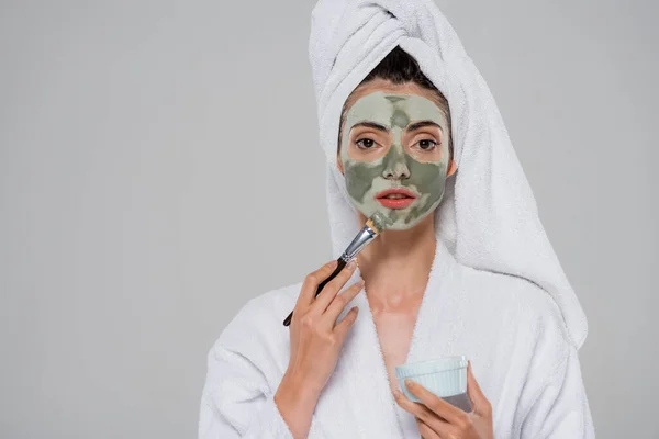 Fiatal Fürdőköpenyben Alkalmazása Agyag Maszk Kozmetikai Kefe Miközben Néz Kamera — Stock Fotó