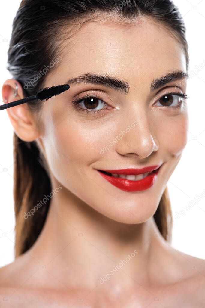 cheerful young woman applying mascara isolated on white 