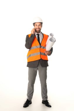 Mutlu mühendis cep telefonunu alıyor ve beyaz arkaplanın planlarını tutuyor 