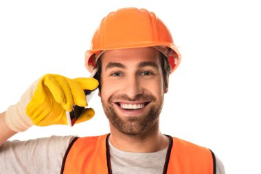 Smiling builder looking at camera while talking on smartphone isolated on white  clipart
