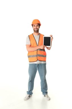 Beyaz arkaplanda boş ekranlı dijital tableti tutan gülümseyen inşaatçının tam uzunluğu 