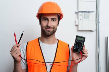 Elektrikli testçi tutan kasklı bir işçi. 