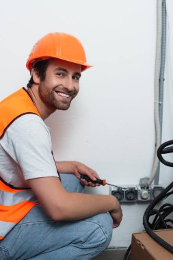Smiling workman holding screwdriver near sockets clipart