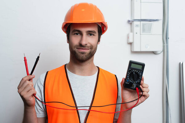 Рабочий в жесткой шляпе с электрическим тестером 