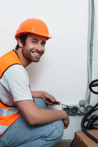 Sonriente Trabajador Sosteniendo Destornillador Cerca Tomas — Foto de Stock