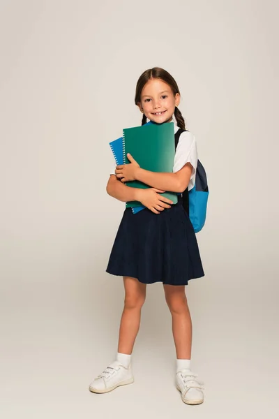 Volledige Weergave Van Vrolijke Schoolmeisje Staan Met Kopieerboeken Grijs — Stockfoto