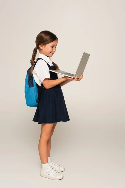 穿着校服的女生在灰色笔记本电脑上的侧视图 — 图库照片