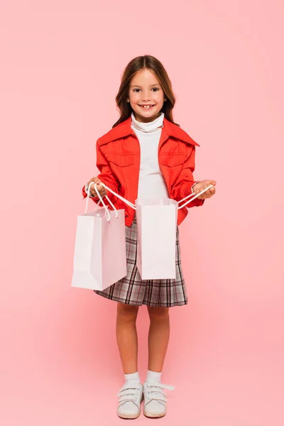 穿着粉色衣服打开购物袋时 一个时髦的孩子对着相机微笑 — 图库照片