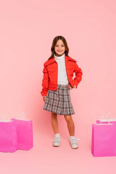 분홍색 쇼핑백 가까이 엉덩이에 소녀가 — 스톡 사진