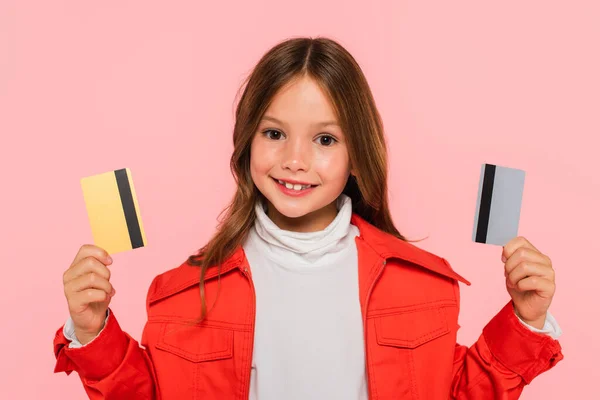 Cheerful Child Trendy Jacket Holding Credit Cards Isolated Pink — Stock Photo, Image