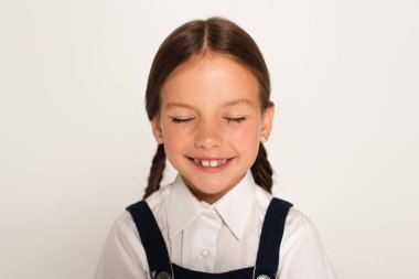 pleased schoolchild smiling with closed eyes isolated on grey clipart