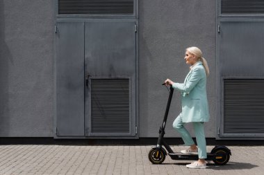 Elektrikli scooter 'ın yanında duran kıdemli iş kadınının yan görüntüsü 