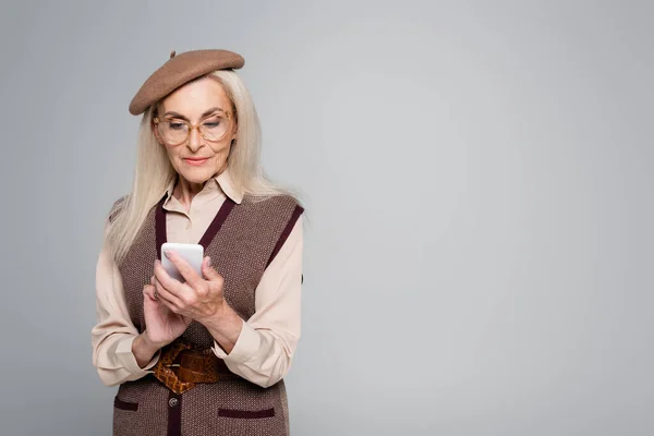 Старша Жінка Береті Окулярах Використовуючи Мобільний Телефон Ізольовано Сірому — стокове фото
