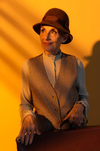 Sorrindo Mulher Sênior Segurando Mala Vintage Fundo Laranja — Fotografia de Stock