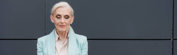 Senior businesswoman standing near building, banner 