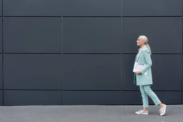 Widok Boku Starszej Businesswoman Gazety Spaceru Pobliżu Budynku Zewnątrz — Zdjęcie stockowe