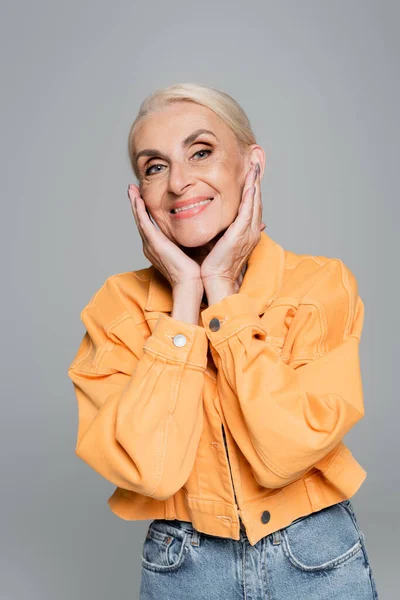 Cheerful Senior Woman Orange Jacket Posing Hands Face Isolated Grey — Stock Photo, Image