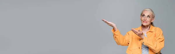 주황색 자켓을 긍정적 고개를 돌리고 고립된 현수막을 가리키며 — 스톡 사진