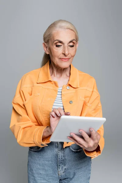 Senior Woman Orange Jacket Using Digital Tablet Isolated Grey — Stock Photo, Image